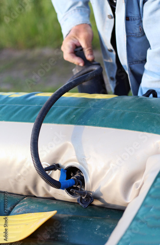 rubber boat is inflated with a hand pump by a man