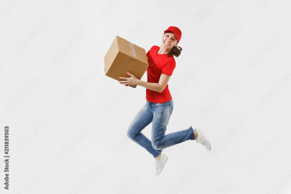 Full length portrait of fun delivery woman in red cap, t-shirt isolated on white background. Female courier or dealer jumping with empty cardboard box. Receiving package. Copy space for advertisement. Full length portrait of fun delivery woman in red cap, t-shirt isolated on white background. Female courier or dealer jumping with empty cardboard box. Receiving package. Copy space for advertisement.