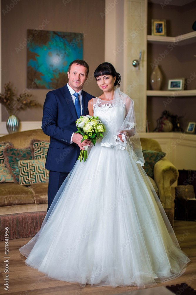 Groom and bride together in background of luxurious room with sofa