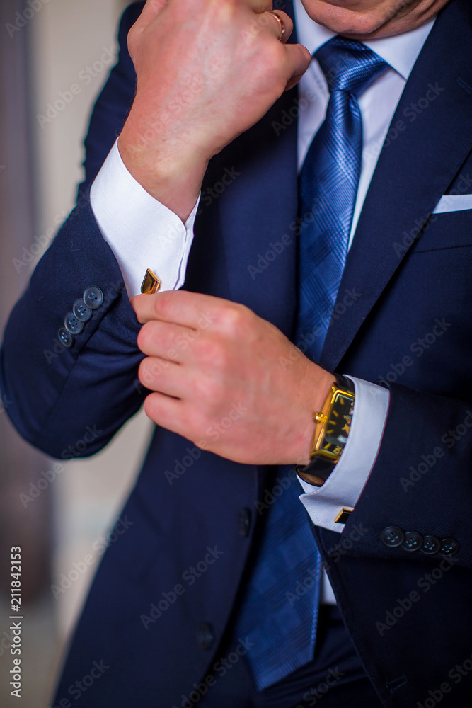 Man in suit, fastens cufflink on sleeve, closeup
