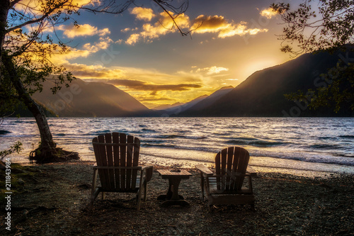 Sunset over Lake Crescent with two wooden chairs on the shore, Olympic National Park, Washington State, USA.