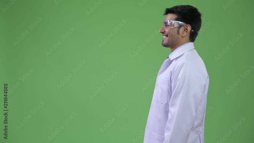 Profile view of young handsome Persian man doctor wearing protective glasses Profile view of young handsome Persian man doctor wearing protective glasses