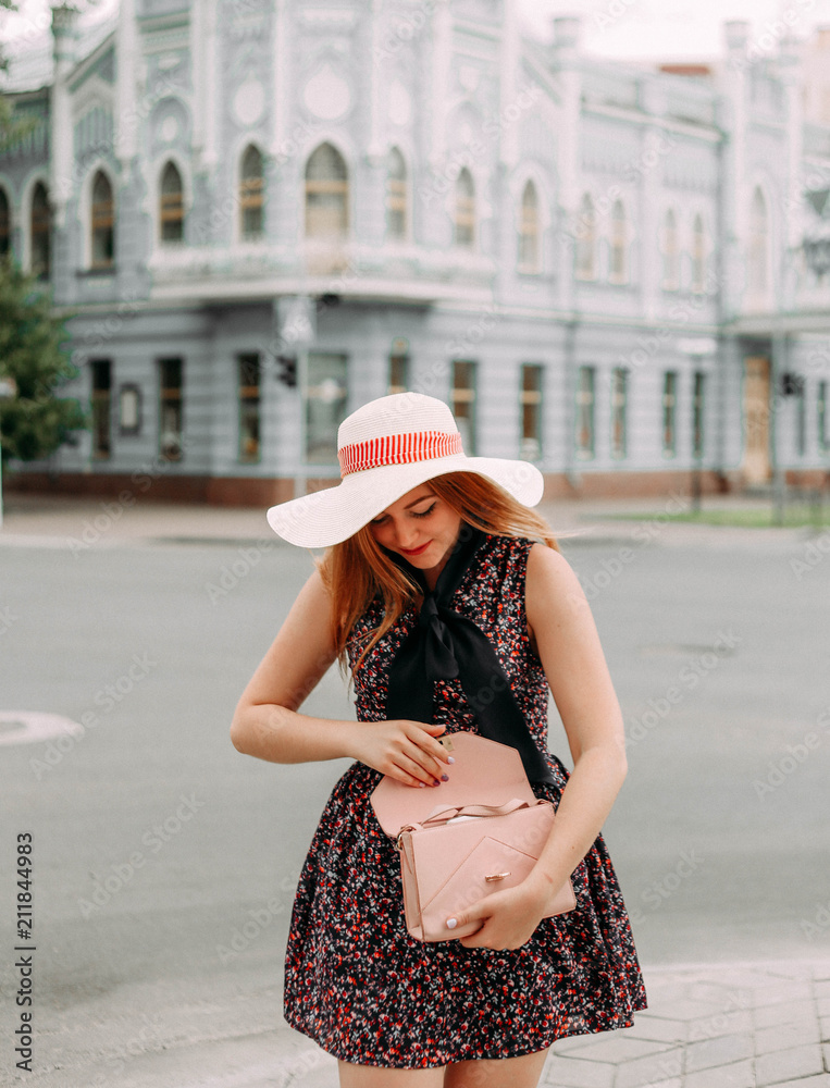 girl in dress hat looks her purse