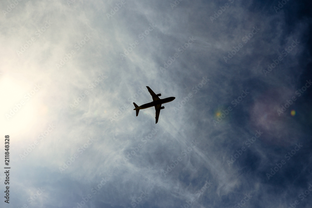 A silhouette of a plane flying overhead on a clear day.