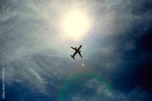 A silhouette of a plane flying overhead on a clear day.