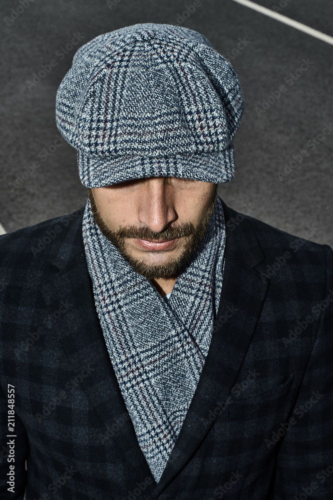 Beautiful portrait of a man in a cap. Cap of different colors and shapes. Autumn portrait, clouds behind and stormy sky. Scarf around the neck in the color of the cap. Face severe, serious. Beautiful portrait of a man in a cap. Cap of different colors and shapes. Autumn portrait, clouds behind and stormy sky. Scarf around the neck in the color of the cap. Face severe, serious.