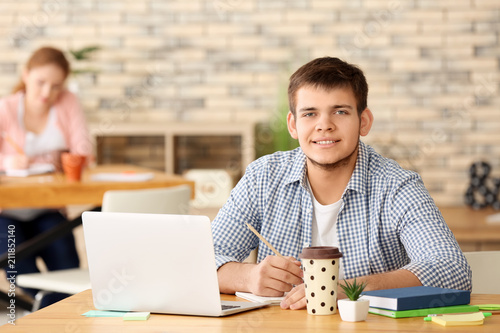 Teenager with laptop studyi...