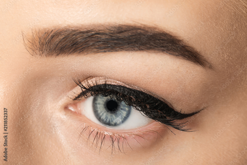 Eye of young woman with beautiful eyebrow after correction, closeup