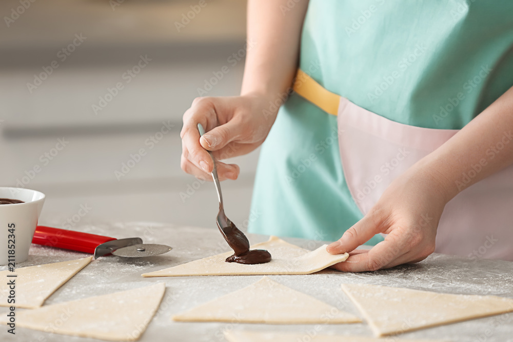 Woman preparing tasty croissants with chocolate paste on table, closeup Woman preparing tasty croissants with chocolate paste on table, closeup