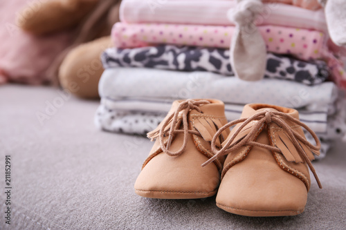 Child shoes and stack of clothes on background