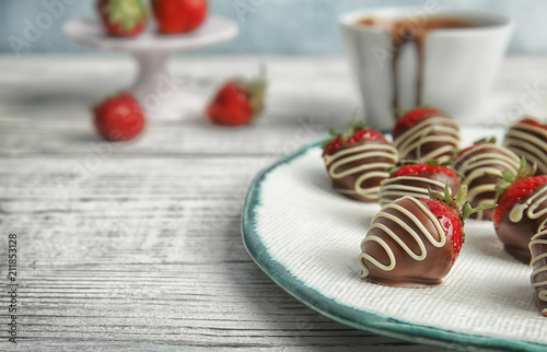 Plate with chocolate covered strawberries on table, closeup