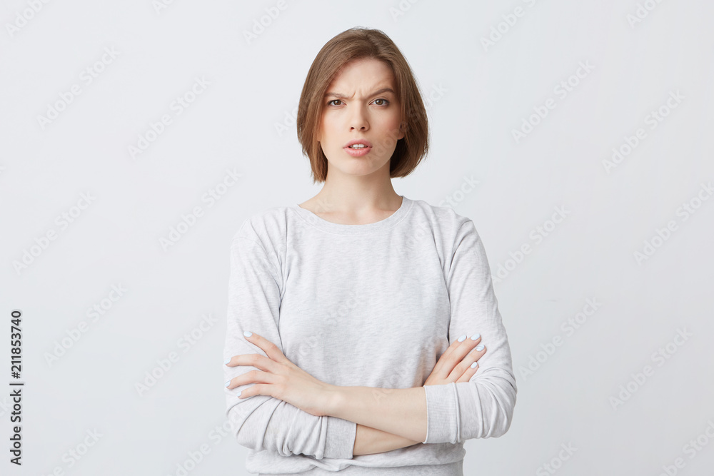 Portrait of serious confused young woman in longsleeve standing with arms crossed and looking confused isolated over white background Feels puzzled Portrait of serious confused young woman in longsleeve standing with arms crossed and looking confused isolated over white background Feels puzzled