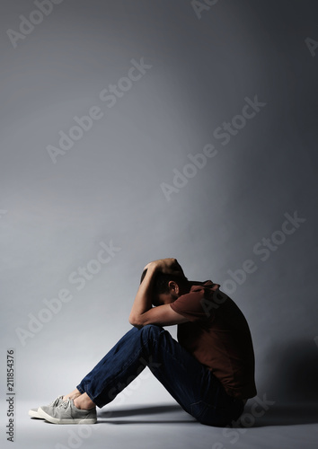 Lonely depressed man sitting on grey background