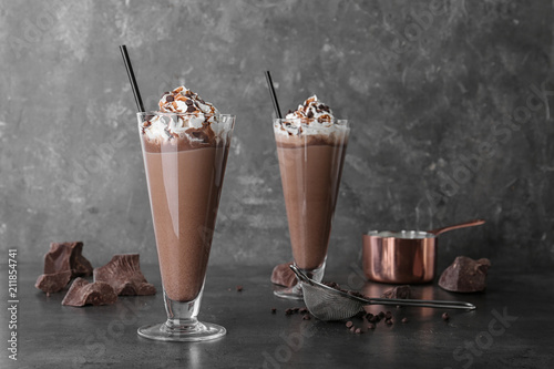 Glasses with chocolate milk shakes on grey table