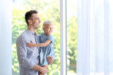 Young man with cute little girl near window at home
