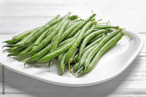 Plate with fresh green French beans on table, closeup