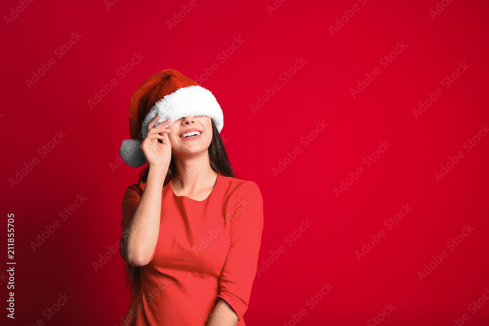 Young beautiful woman in Santa hat on color background. Christmas celebration