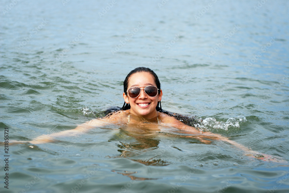 A young woman swimming in a natural water basin.