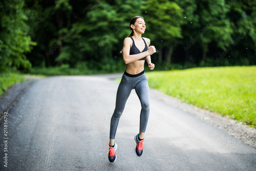 Young lady running. Woman runner running through the spring park road. Workout in a Park. Beautiful fit Girl. Fitness model outdoors. Weight Loss Young lady running. Woman runner running through the spring park road. Workout in a Park. Beautiful fit Girl. Fitness model outdoors. Weight Loss