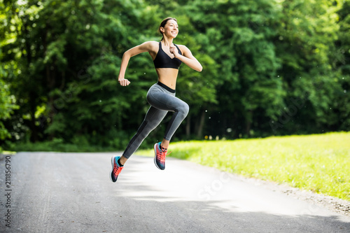 Morning of young fitness woman running outdoors in the park