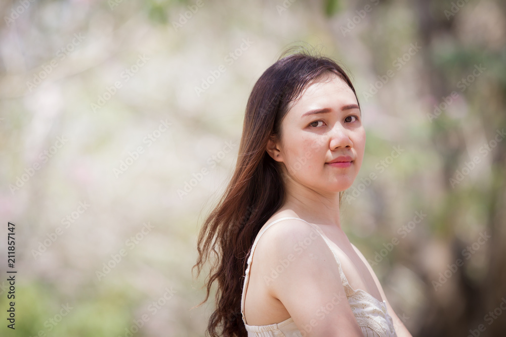 Asian women aged between 25-30 years old posting on natural blurred background close up. Asian women aged between 25-30 years old posting on natural blurred background close up.