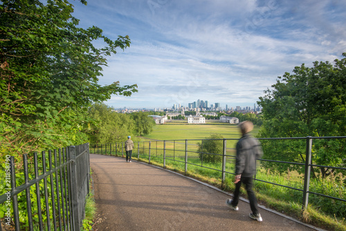 Tourist walking in Greenwich Park with Canary Wharf in the background, London