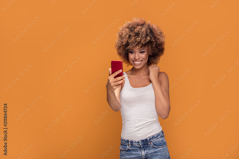 Cheerful afro woman using smart phone. Cheerful afro woman using smart phone.
