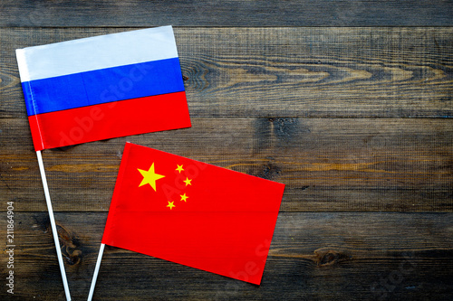 China-Russia relations. Country cooperation. Russian and Chinese flags on dark wooden background top view copy space