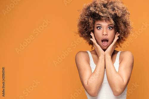 Surprised amazed beautiful afro woman with wide open mouth.