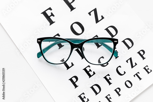 Glasses on eyesight test on white background top view copy space