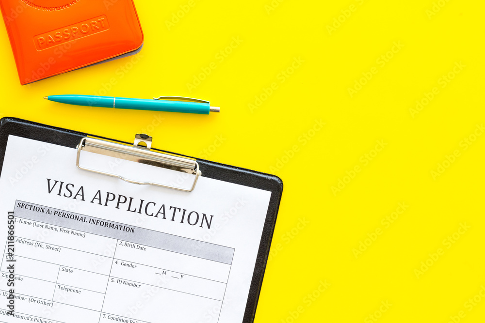 Visa prosessing. Registration of visas. Visa application form and pen on yellow background top view copy space Visa prosessing. Registration of visas. Visa application form and pen on yellow background top view copy space