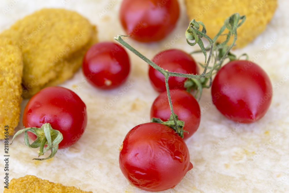 Close-up shot of chicken nuggets and small red fresh tomatoes on the wide white plate as a breakfast Close-up shot of chicken nuggets and small red fresh tomatoes on the wide white plate as a breakfast
