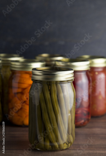 Various Types of Canned Vegetables on a Wooden Table in a Dark Environment