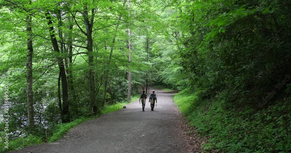 Two fisherman are walking in the forest after fishing Two fisherman are walking in the forest after fishing