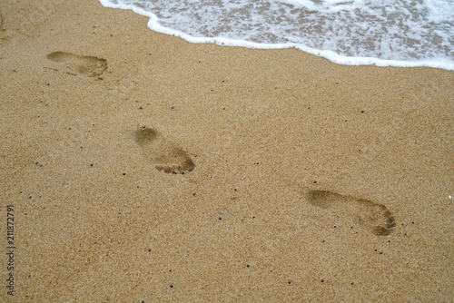  footprints on the beach sand with sea wave