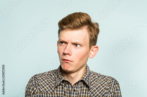 amazed astonished shocked dazed impressed stunned man looking sideways. portrait of a young guy on light background. emotion facial expression. feelings and people reaction.
