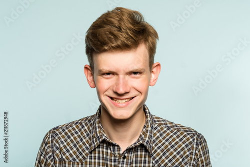 murderous psycho smile. crazy killer lunatic man grinning. portrait of a young guy on light background. emotion facial expression. feelings and people reaction. photo