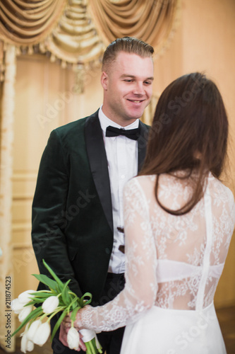 Portrait of the young beautiful couple who is standing face to face indoor on their wedding day