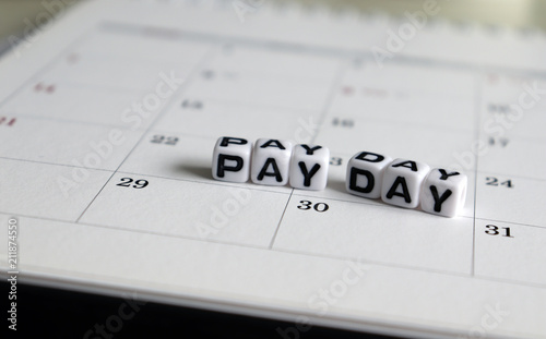 A white cube arranged in the word ’PAY DAY ' on the calendar. photo