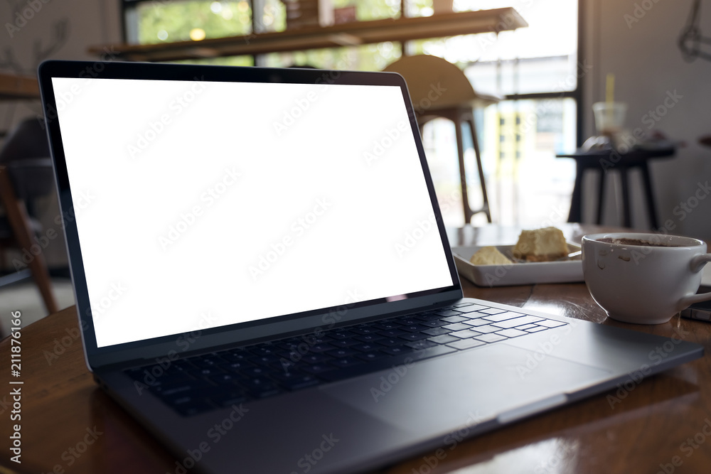 Mockup image of laptop with blank white desktop screen with coffee cup and cake on wooden table in modern cafe Mockup image of laptop with blank white desktop screen with coffee cup and cake on wooden table in modern cafe