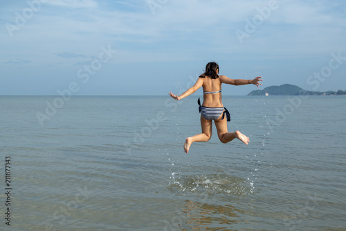 Teenage wearing bikini and jump at the beach.