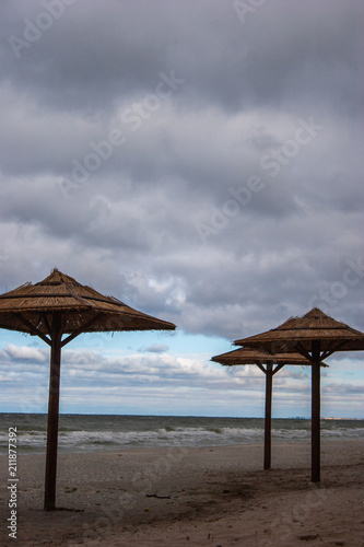 Straw umbrellas from the sun at sea. Cloudy weather and stormy sea.
