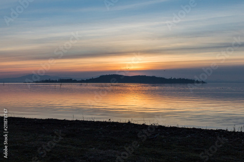 A shoot of a sunset over a lake  with sun coming down behind an island