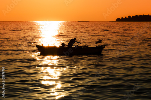 Fototapeta Naklejka Na Ścianę i Meble -  Small boat with a man at sunset