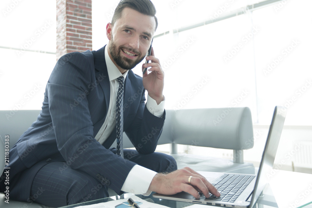 Businessman talking on smartphone and typing text on laptop Businessman talking on smartphone and typing text on laptop