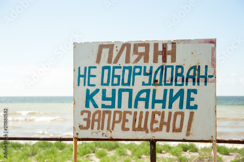 Warning sign on the shore. Text in Russian: the beach is not equipped. swimming is forbidden © Serenkonata
