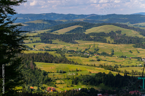 A panorama of green hills with dark spots of high wood in the Carpathians © adamchuk_leo