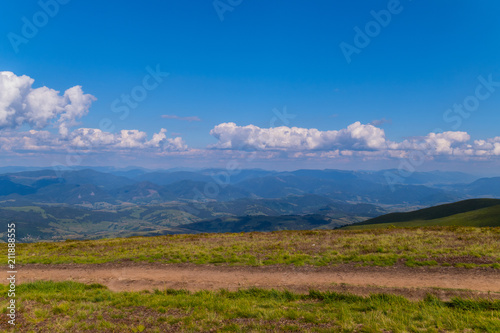 The top view of the huge gently sloping green mountain ranges and the blue boundless sky