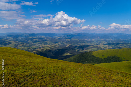 The green grassy top of the mountain with a beautiful view around for many kilometers up to the horizon line.