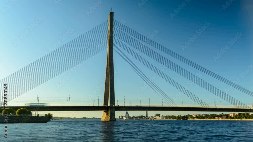 Timelapse of traffic on cable bridge in Riga with people canoeing nearby Timelapse of traffic on cable bridge in Riga with people canoeing nearby